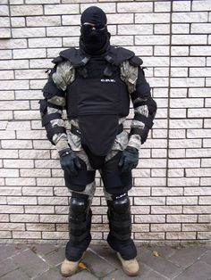 a man in full gear standing next to a brick wall