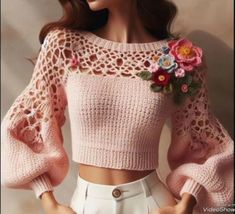 a doll is wearing a pink sweater with flowers on it