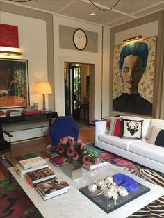 a living room filled with furniture and paintings on the wall next to a coffee table