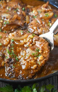 meat and onions are being cooked in a skillet with a ladle on the side