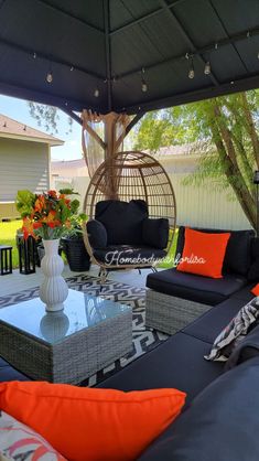 an outdoor living area with black couches and orange pillows