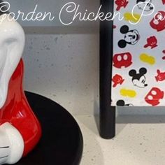 there is a red and white figurine sitting on a black table next to a mickey mouse chair