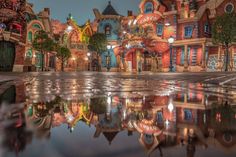 an image of a city at night with lights and buildings reflected in the wet pavement