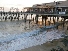 the ocean and pier at sunset with waves coming in