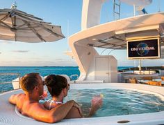 two people sitting in an outdoor jacuzzi on the deck of a boat looking out at the ocean