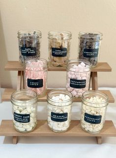 jars filled with marshmallows sitting on top of a wooden shelf next to each other