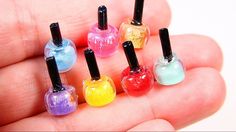 small colorful nail polish bottles in the palm of someone's hand with their thumbnails