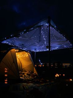 a tent is lit up at night with stars on the roof and in the background