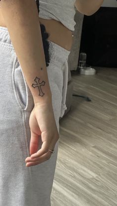 a person with a cross tattoo on their arm