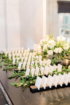 the table is set up with place cards and greenery for guests to sit at