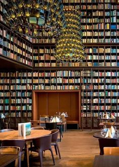 a library filled with lots of books next to tables and chairs in front of them