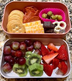 two trays filled with fruit and crackers on top of a table