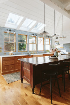 a large kitchen with wooden floors and skylights above the countertop, along with two dining chairs