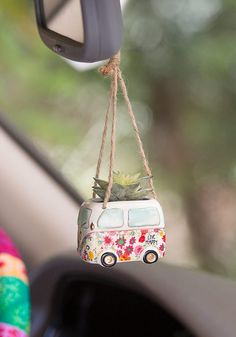 a mini van is hanging from a rope with succulents in the rear view mirror