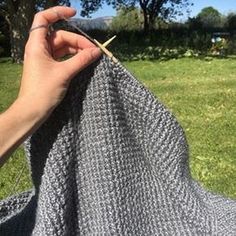 someone is knitting in the yard with their hand on it's shoulder and there is a small wooden stick sticking out of the yarn