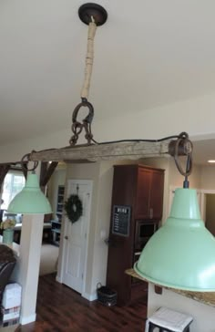 a kitchen with two green lamps hanging from the ceiling and a light fixture above it