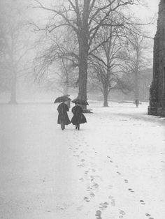 two people walking in the snow with umbrellas over their heads and footprints on the ground