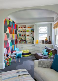 a living room filled with lots of furniture and colorful decor on the walls, along with bookshelves