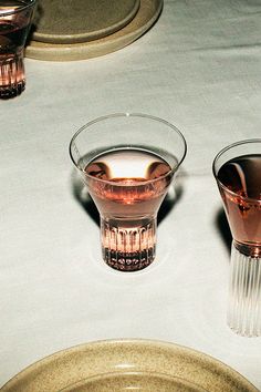 two glasses with liquid in them sitting on a table