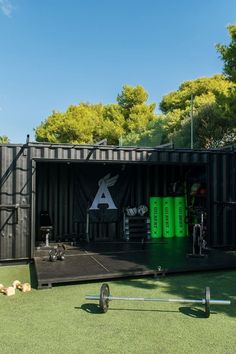 an open shipping container with exercise equipment on the grass and trees in the back ground