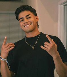 a young man wearing a black t - shirt is making the peace sign with his hands