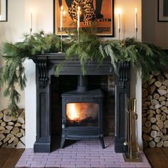 the fireplace is decorated with greenery and candles