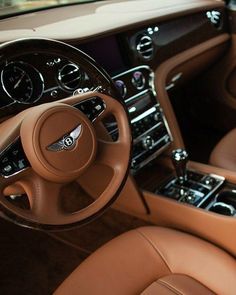 the interior of a luxury car with brown leather seats and steering wheel, including center console