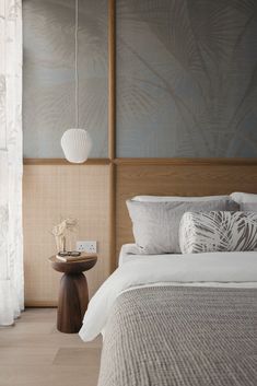 a bed with white sheets and pillows in a bedroom next to a wall mounted lamp