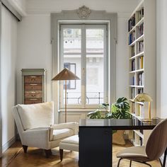 a living room filled with furniture and a book shelf next to a window covered in books