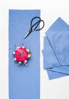 a pair of scissors sitting on top of a piece of blue paper next to some fabric