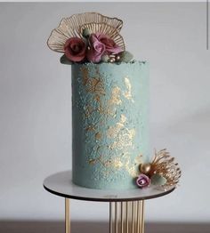 a blue and gold wedding cake with flowers on top