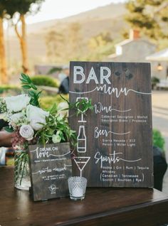 a wooden sign sitting on top of a table next to a vase filled with flowers