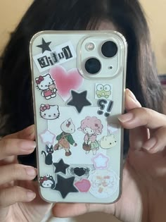 a woman holding up her phone case with stickers on it