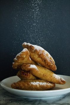 powdered sugar coated doughnuts on a white plate