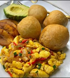 a white plate topped with eggs, corn and other foods next to avocado