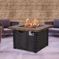 an outdoor fire pit sitting on top of a patio next to some chairs and tables