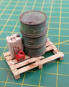 a green container sitting on top of a wooden pallet next to a red can