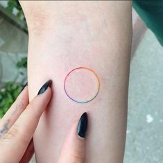 a woman's arm with black nails and a rainbow ring tattoo on her left side