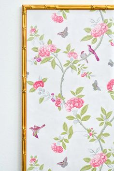 a wall hanging on the side of a white wall with pink flowers and green leaves