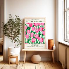 a pink flower market poster hangs on the wall next to a wooden bench and potted plant