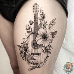 a woman's thigh with flowers and an acoustic guitar