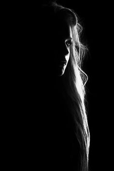 a black and white photo of a woman's face with long hair in the dark