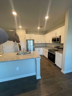 a kitchen with white cabinets and an island in front of a stove top oven next to a microwave