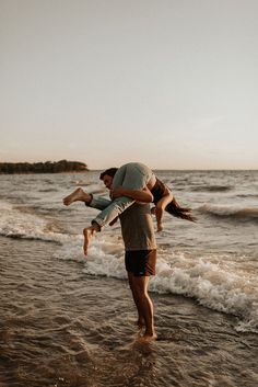 two people are playing in the water at the beach while one person is holding another