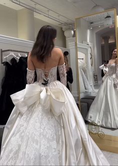 a woman in a wedding dress looking at herself in the mirror