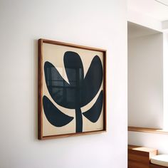 an abstract painting hangs on the wall next to a wooden bench in a white room