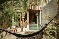 a hammock is in the middle of a tropical courtyard with a pool and palm trees