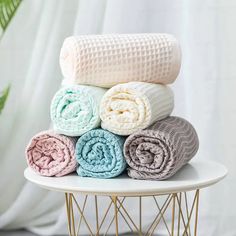 stack of folded towels on white table with green plant in background