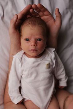 a man holding a baby in his arms while laying on top of a white bed