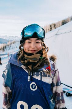 a woman standing on top of a snow covered slope wearing skis and goggles